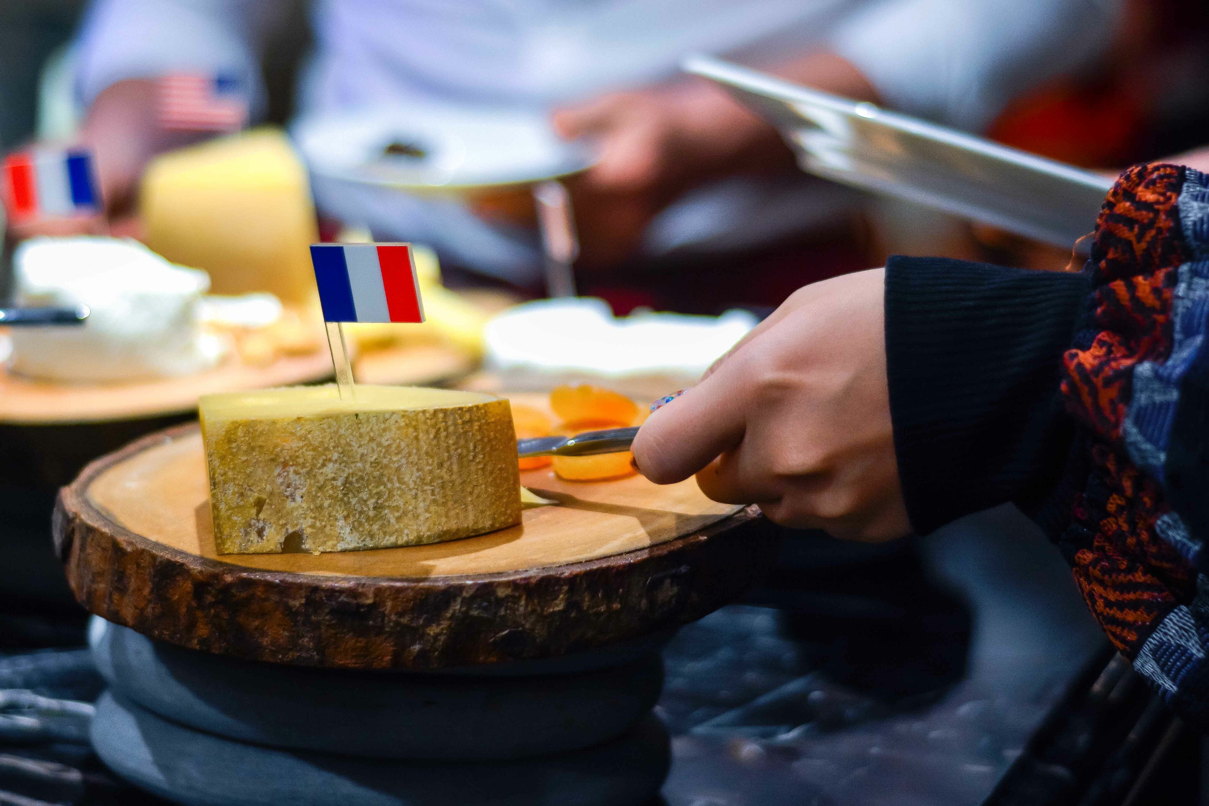 french cheese on wooden slab with persons hand