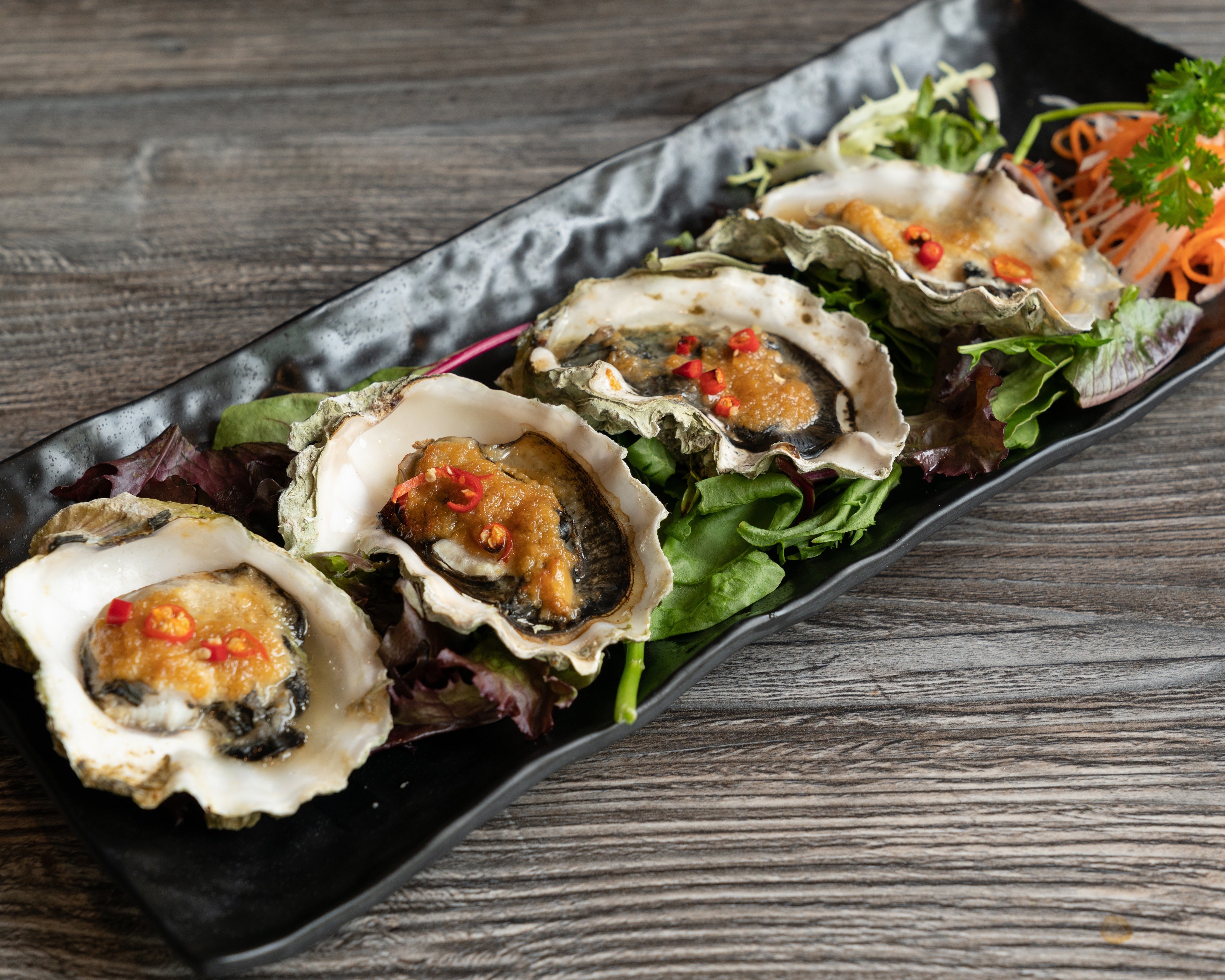 oysters with chilis on a black serving platter