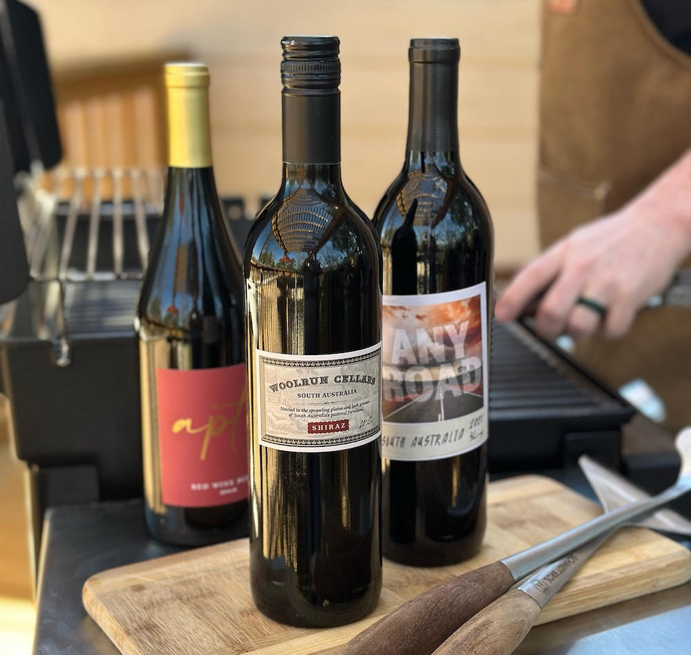 three red wine bottles by a grill
