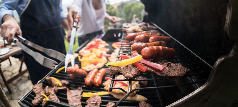 meat and bell pepper on a bbq grill with people with tongs