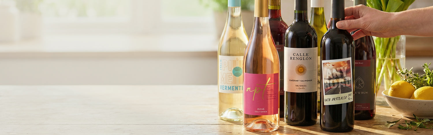 Mixed assortment of wines on spring table, withe lemons on the right, a hand reaching for the wine.