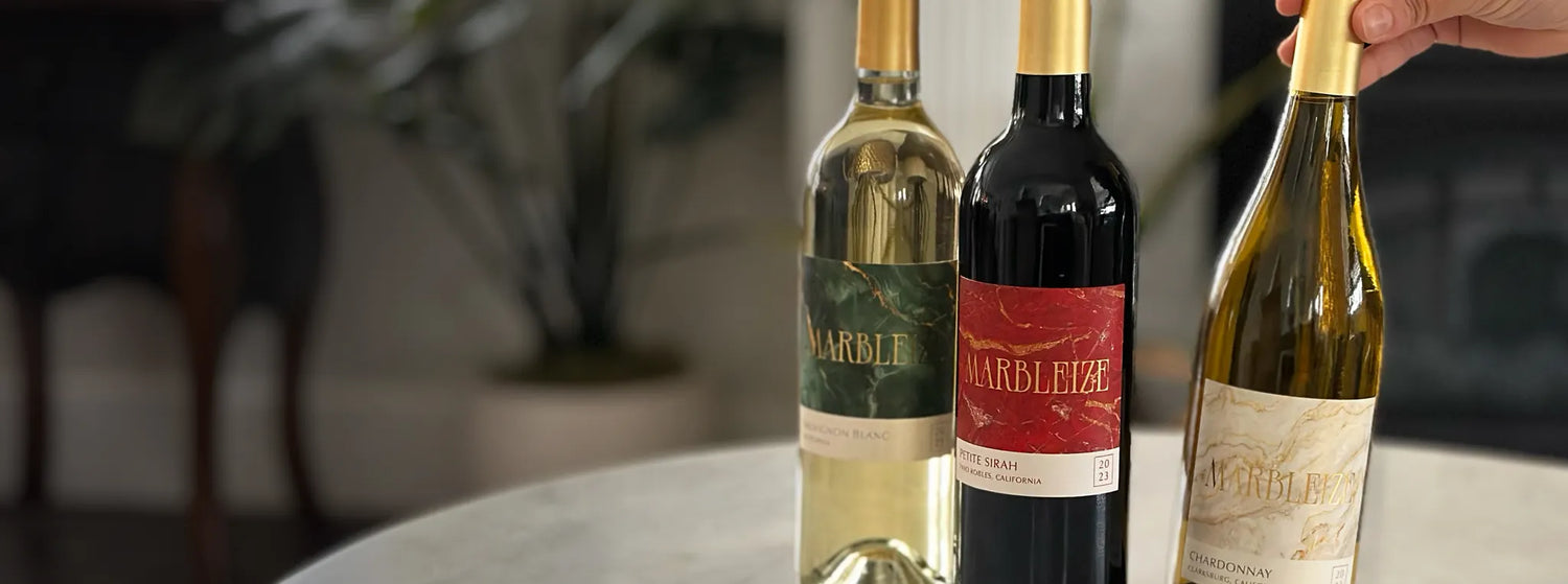 Hand placing a bottle of Marbleize wine next to other Marbleize white and red wine bottles.