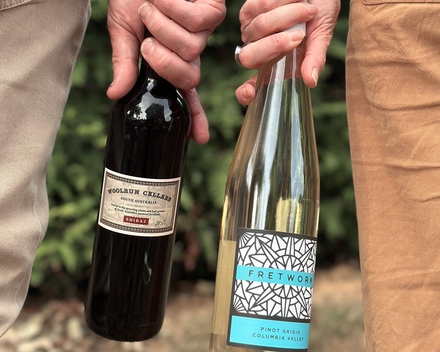two people standing next to each other holding one bottle each